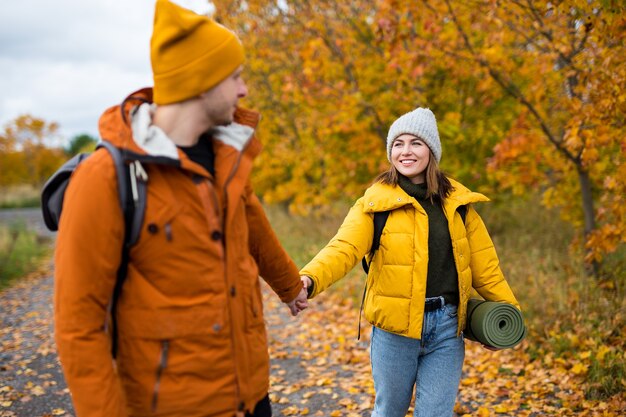 Joven hermosa pareja de enamorados caminando en el bosque de otoño con mochilas