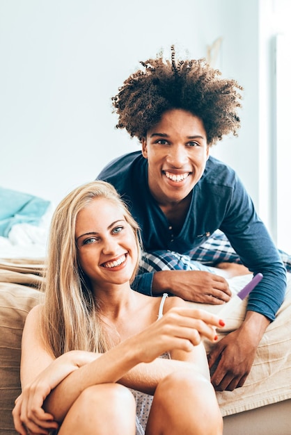 Joven hermosa pareja interracial en la cama feliz con prueba de embarazoxA