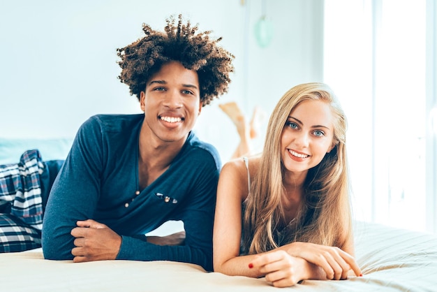 Una joven y hermosa pareja interracial relajada acostada en la cama abrazándose