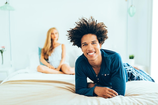 Una joven y hermosa pareja interracial relajada acostada en la cama abrazándose