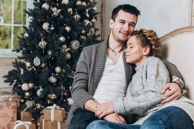 Joven hermosa pareja en la sala decorada de Navidad. Navidad y año nuevo concepto