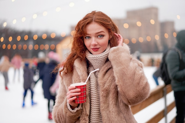 Joven hermosa pelirroja en la pista de hielo