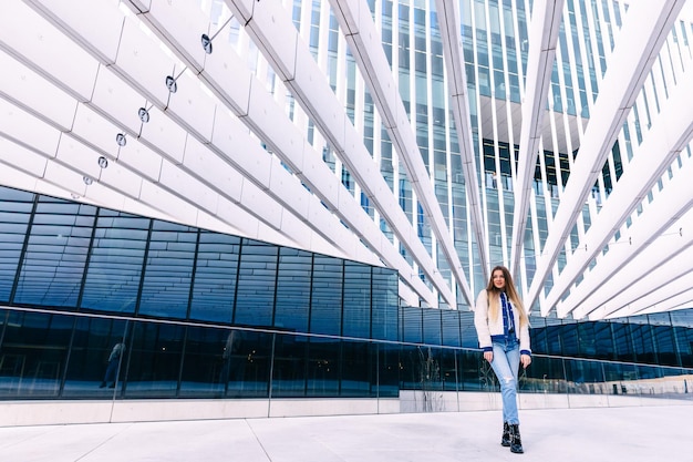 Foto una joven hermosa se para pensativa en la calle contra el fondo de un edificio de oficinas de vidrio