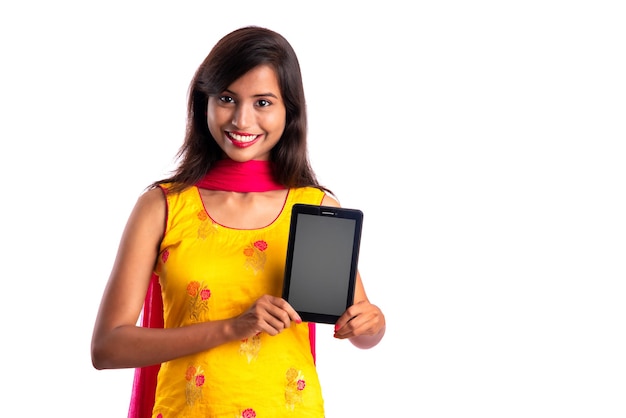 Una joven hermosa que muestra una pantalla en blanco de un teléfono inteligente, móvil o tableta en un fondo blanco
