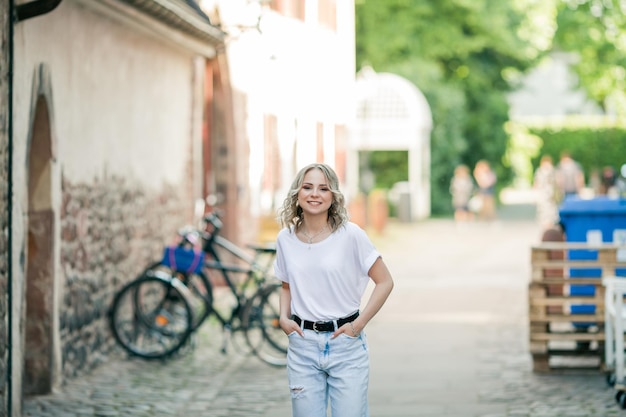 Joven hermosa rubia de ojos azules en el centro de una ciudad europea Retrato de un modelo elegante en ropa casual Juventud feliz