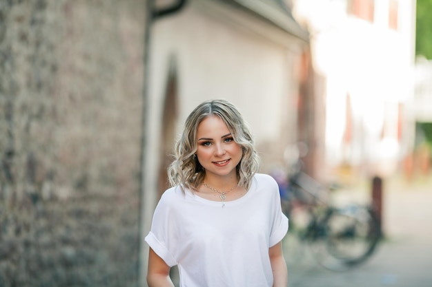 Joven hermosa rubia de ojos azules en el centro de una ciudad europea Retrato de un modelo elegante en ropa casual Juventud feliz