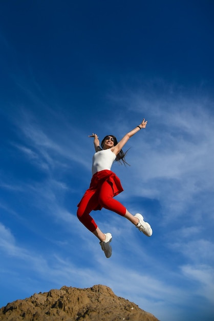 Una joven hermosa en un salto contra el cielo Beauty Color