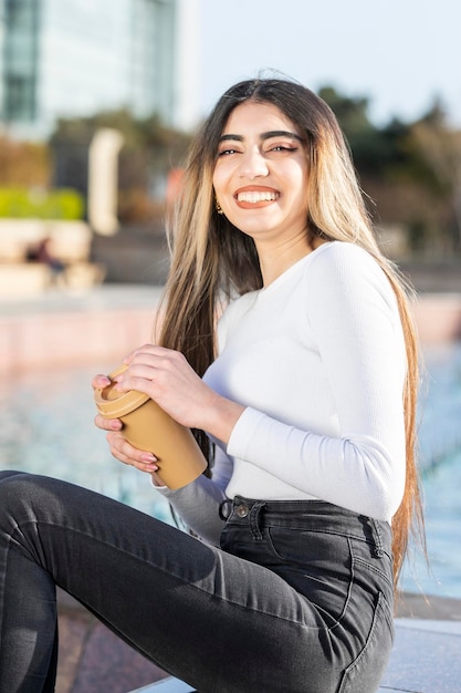 Una joven hermosa sosteniendo una taza de café y riendo Foto de alta calidad