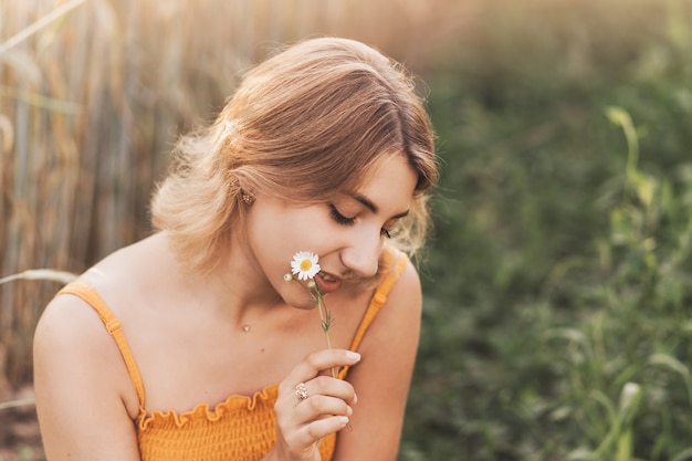 Una joven hermosa sostiene una flor de manzanilla