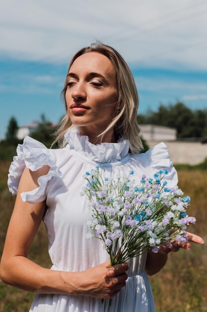 Una joven hermosa sostiene flores en sus manos.