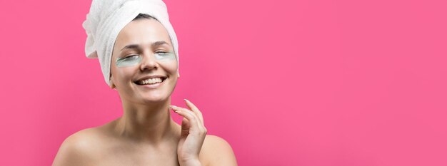 Una joven hermosa con una toalla blanca en la cabeza usa parches de gel de colágeno debajo de los ojos Máscara debajo de la cara de tratamiento de los ojos