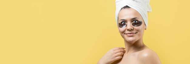 Foto una joven hermosa con una toalla blanca en la cabeza usa parches de gel de colágeno debajo de los ojos máscara debajo de la cara de tratamiento de los ojos