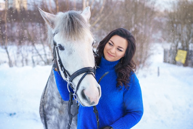 Una joven con un hermoso caballo blanco de invierno.