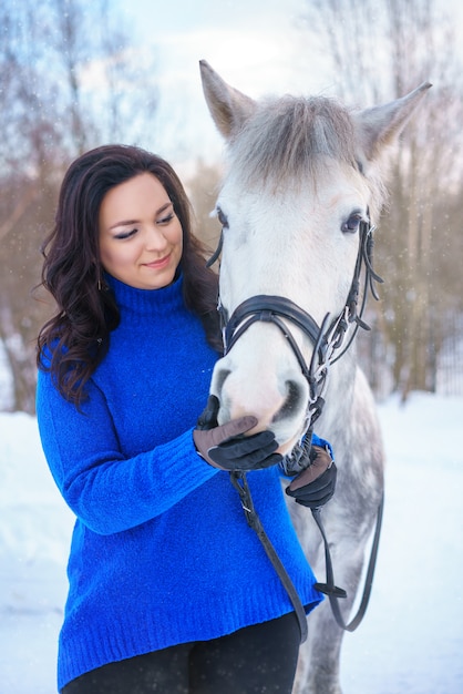 Una joven con un hermoso caballo blanco de invierno.