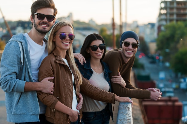 Foto joven y hermoso. grupo de jóvenes de pie cerca uno del otro en el puente y mirando a la cámara con una sonrisa