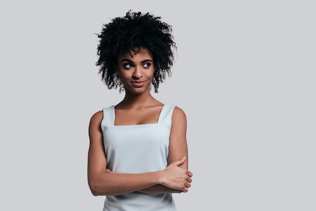 Foto joven y hermoso. hermosa joven africana en ropa casual manteniendo los brazos cruzados