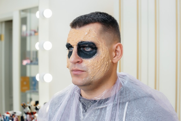 Un joven con un hermoso maquillaje espeluznante en forma de calavera para la fiesta de Halloween en el primer plano del estudio. Feliz concepto de Halloween.