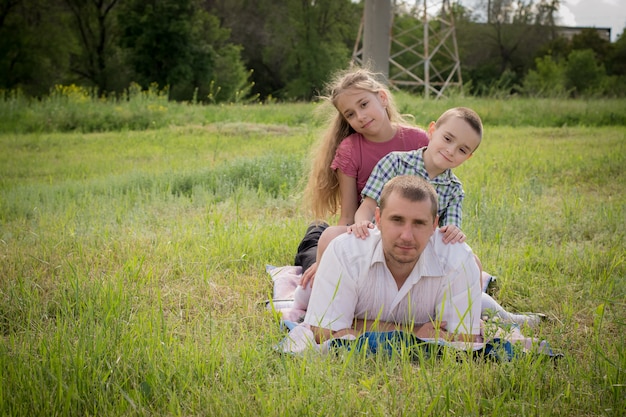 Un joven hermoso con sus hijos pequeños en el parque.