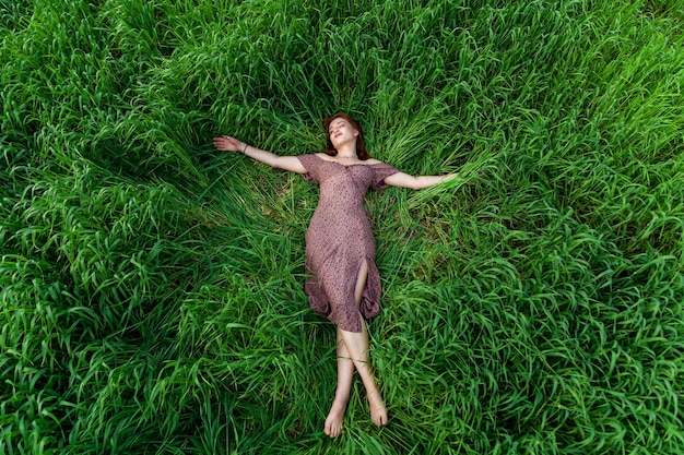Una joven con un hermoso vestido yace en la hierba verde