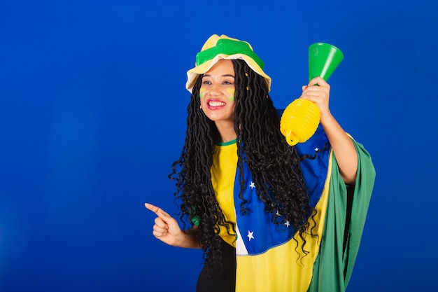 Joven hincha de fútbol brasileña negra bailando con los dedos levantados