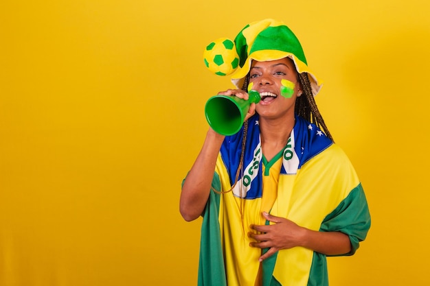 Foto joven hincha de fútbol brasileño de mujer negra usando teléfono para anunciar algo
