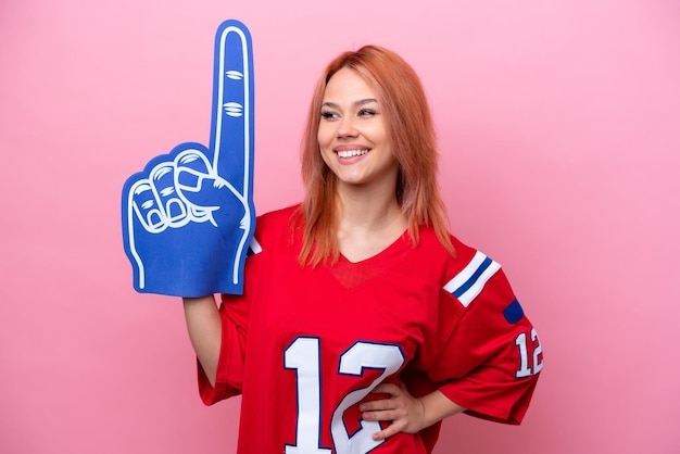 Foto joven hincha de rugby rusa aislada de fondo rosa posando con los brazos en la cadera y sonriendo