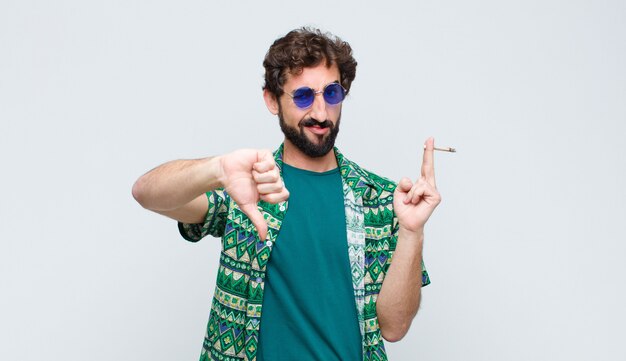 Joven hippie fumando un porro contra la pared blanca