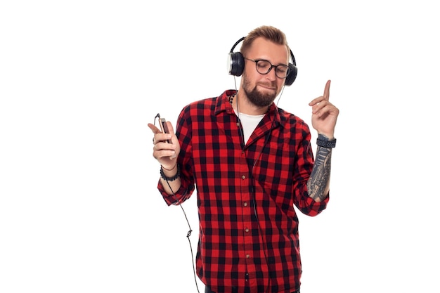 Joven hipster con camisa a cuadros y gafas con auriculares que se ven felices con fondo blanco. Disparo de estudio. copia espacio