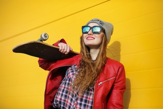 Una joven hipster está montando una patineta Chicas amigas paseando por la ciudad con una patineta Deportes de primavera en la calle con una patineta