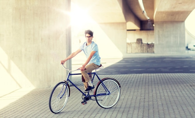 joven hipster montando una bicicleta de engranajes fijos