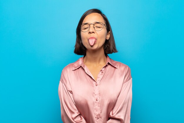 Joven hispana con actitud alegre, despreocupada y rebelde, bromeando y sacando la lengua, divirtiéndose