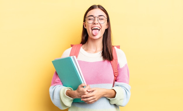 Foto joven hispana con actitud alegre y rebelde, bromeando y sacando la lengua. concepto de estudiante