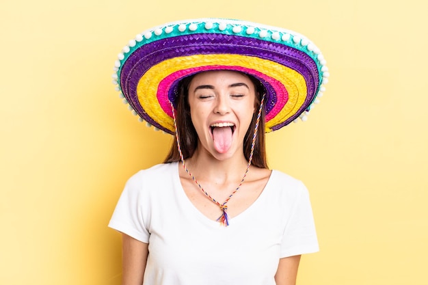 Joven hispana con actitud alegre y rebelde, bromeando y sacando la lengua. concepto de sombrero mexicano