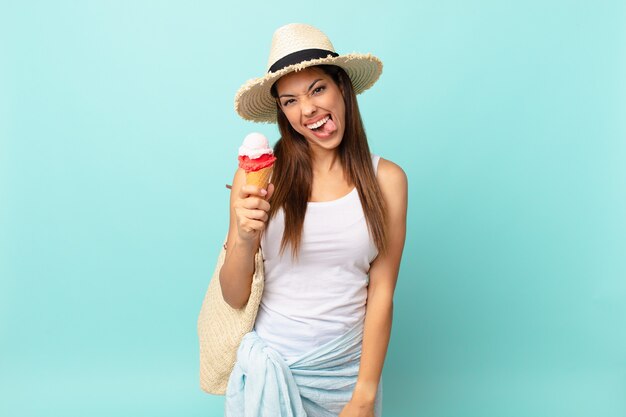 Joven hispana con actitud alegre y rebelde, bromeando y sacando la lengua y sosteniendo un helado. concepto sumergible