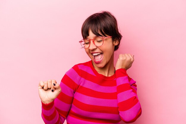 Joven hispana aislada de fondo rosa bailando y divirtiéndose