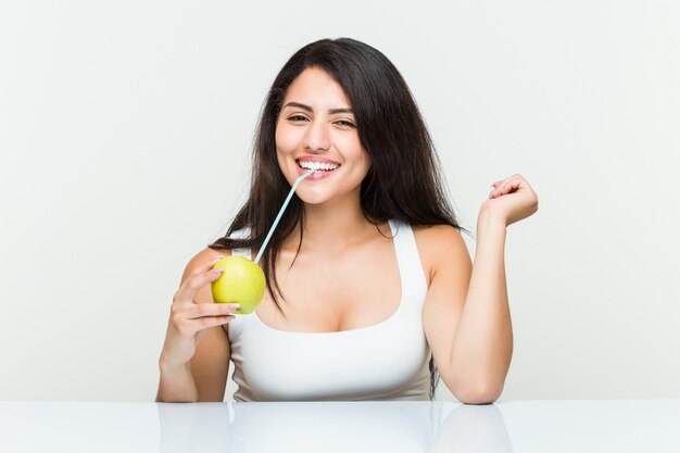 Joven hispana bebiendo un jugo de manzana con una pajita