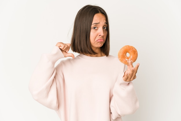 Joven hispana comiendo un donut se siente orgullosa y segura de sí misma, ejemplo a seguir.