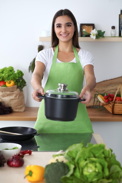 Joven hispana en un delantal verde cocinando en la cocina Ama de casa encontró una nueva receta para su sopa