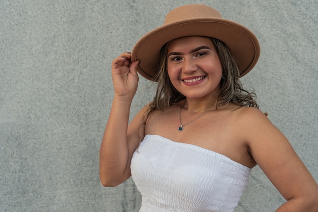 Joven hispana delante de una pared gris con un vestido