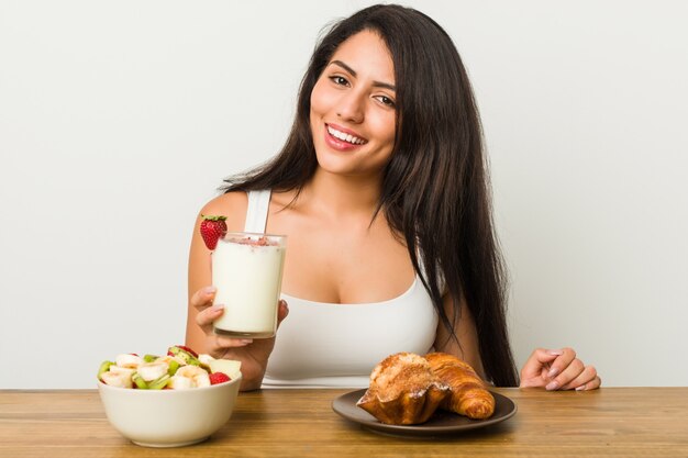 Joven hispana desayunando en la mesa