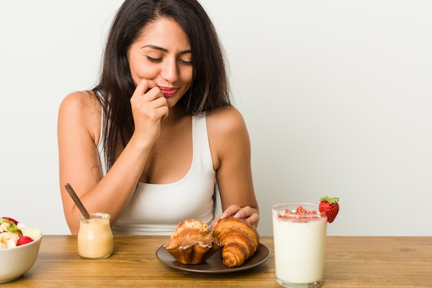 Joven hispana desayunando en la mesa