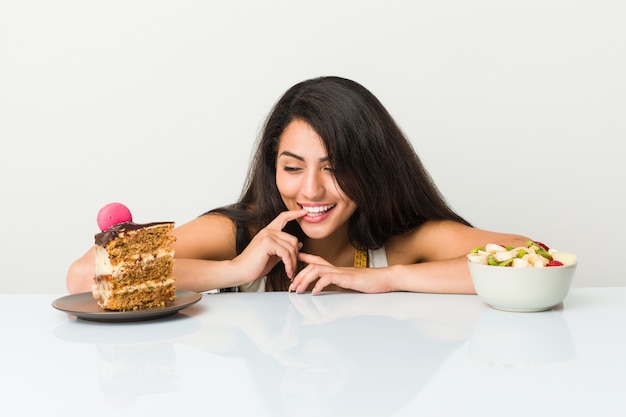 Joven hispana eligiendo entre tarta o frutero