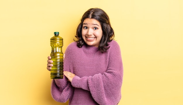 Joven hispana encogiéndose de hombros, sintiéndose confusa e insegura. concepto de aceite de oliva