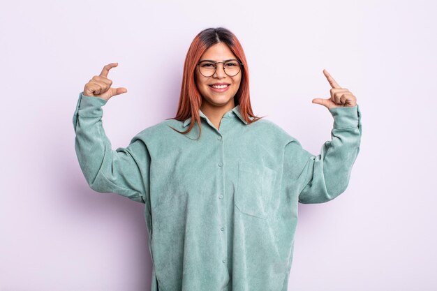 Joven hispana enmarcando o esbozando su propia sonrisa con ambas manos, luciendo positiva y feliz, concepto de bienestar