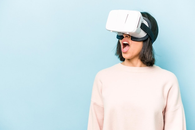 Joven hispana con gafas virtuales aisladas de fondo azul