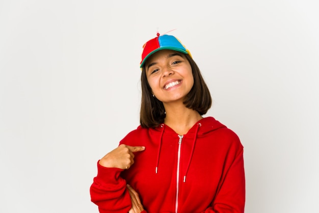 Foto joven hispana con una gorra con hélice persona aislada apuntando con la mano a un espacio de copia de camisa, orgulloso y seguro