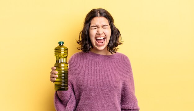 Joven hispana gritando agresivamente, luciendo muy enojada. concepto de aceite de oliva