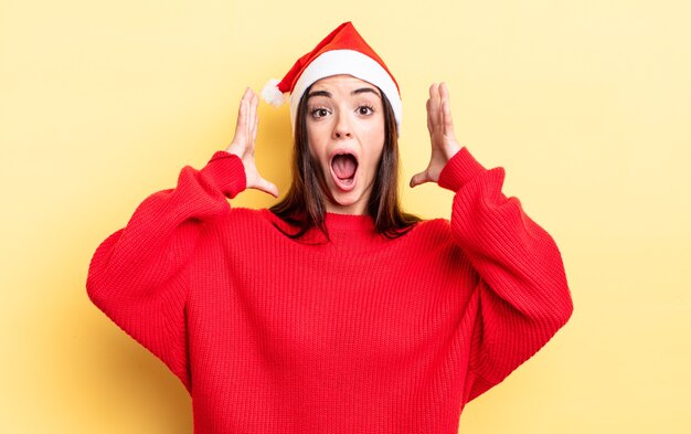 Joven hispana gritando con las manos en el aire. concepto de navidad y año nuevo