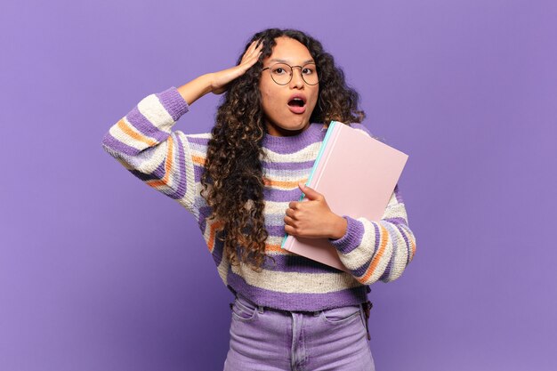 Joven hispana luciendo feliz, asombrada y sorprendida, sonriendo y dándose cuenta de buenas e increíbles noticias. concepto de estudiante