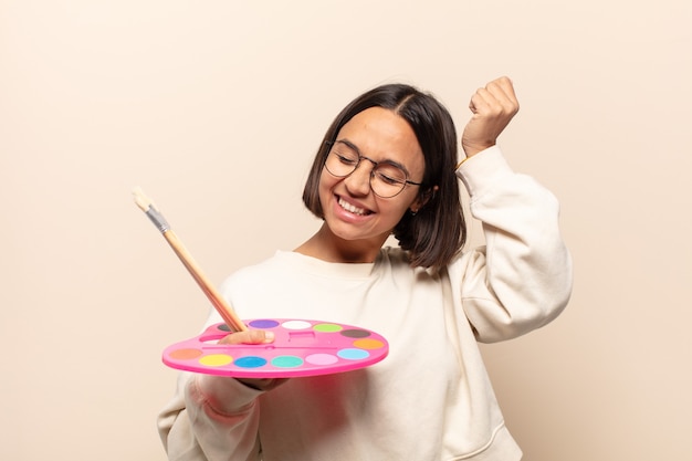 Joven hispana luciendo feliz, asombrada y sorprendida, sonriendo y dándose cuenta de buenas noticias increíbles e increíbles